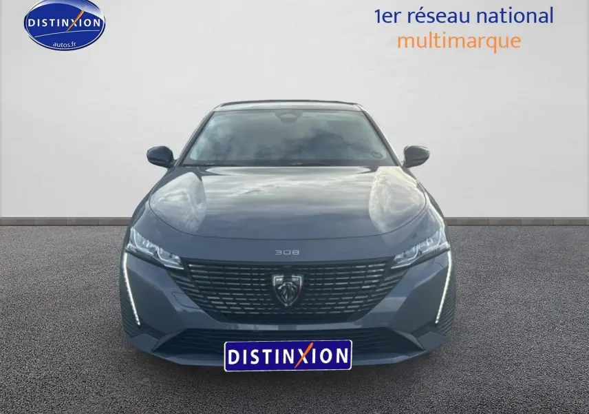 Vue frontale d'une Peugeot 308 gris sélénite 2024 avec calandre noire et feux LED verticaux allumés.