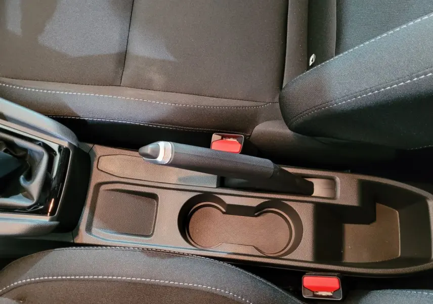 Vue rapprochée de la console centrale noire avec frein à main manuel et porte-gobelets de la Renault Clio gris foncé.