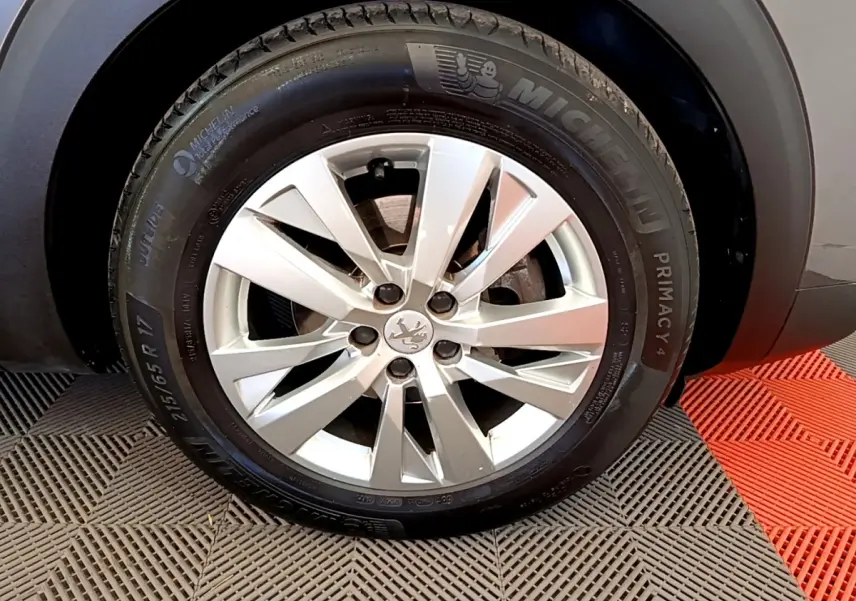 Gros plan sur la roue avant droite d’un Peugeot 5008 gris clair, jante alliage et pneu Michelin Primacy 4.