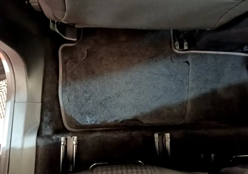 Vue intérieure du plancher arrière du Peugeot 5008 gris clair, montrant les rails des sièges amovibles et la moquette sombre.