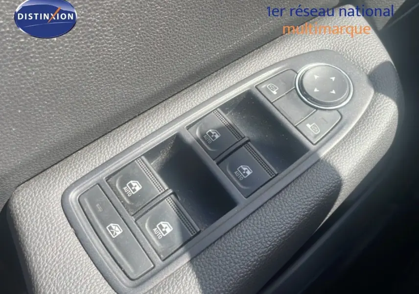 Gros plan sur les commandes de lève-vitres et rétroviseurs côté gauche d’une Renault Clio blanche, intérieur noir.