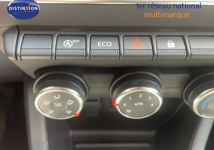 Gros plan sur les commandes de climatisation et boutons de fonction d’une Renault Clio blanche, intérieur noir.