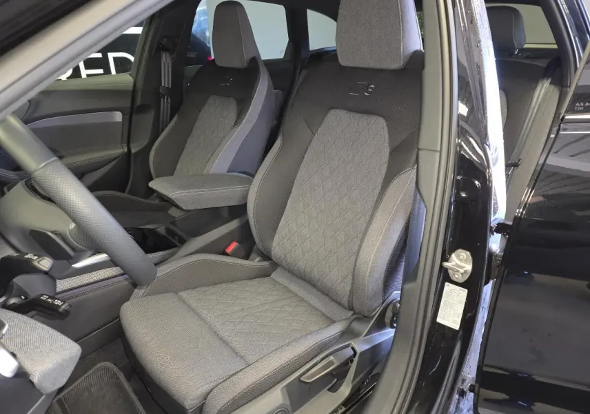 Vue intérieure côté conducteur de l'Audi A5 Avant noire, sièges sport tissu gris avec logo S brodé.