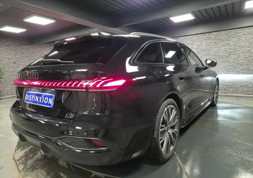 Audi A5 Avant noir vue 3/4 arrière droit, feux arrière LED allumés et jantes 19 pouces style V.