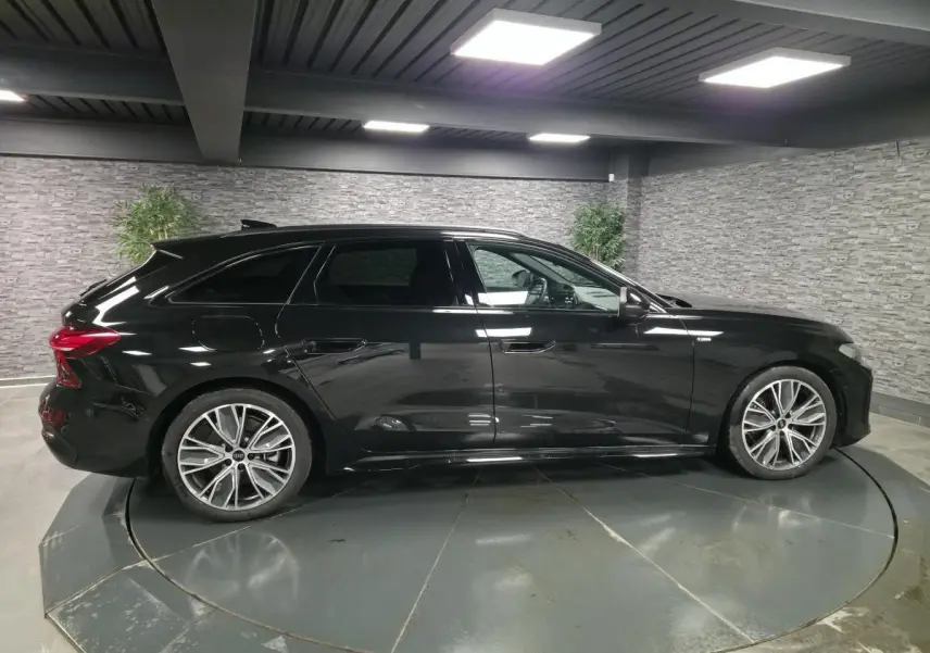 Audi A5 Avant 2025 noir vue de profil côté gauche, jantes 19 pouces et vitres arrière surteintées visibles.