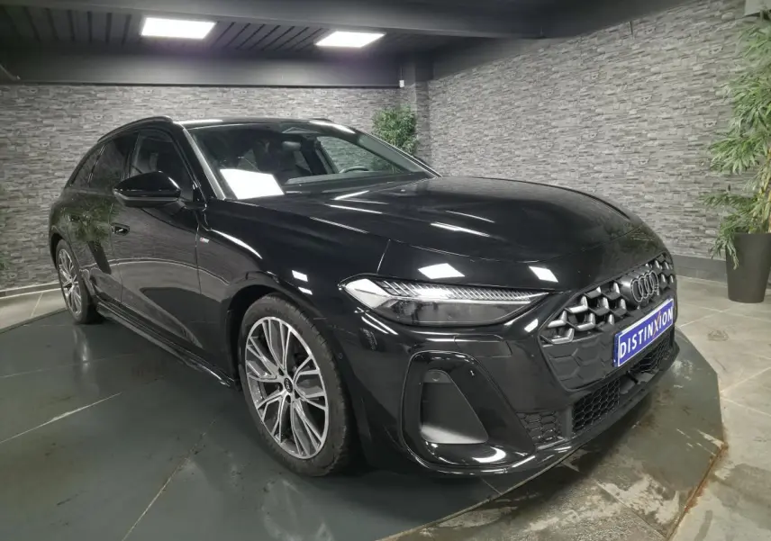 Audi A5 Avant S line noire vue 3/4 avant droit avec jantes 19 pouces et calandre hexagonale distinctive.