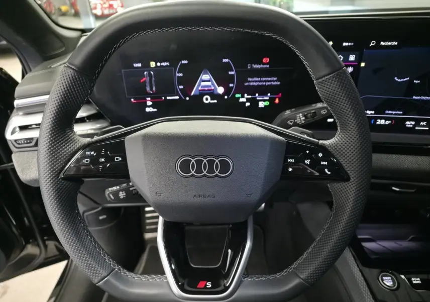 Vue rapprochée du volant sport en cuir noir avec logo Audi S et tableau de bord numérique d'une Audi A5 Avant 2025.
