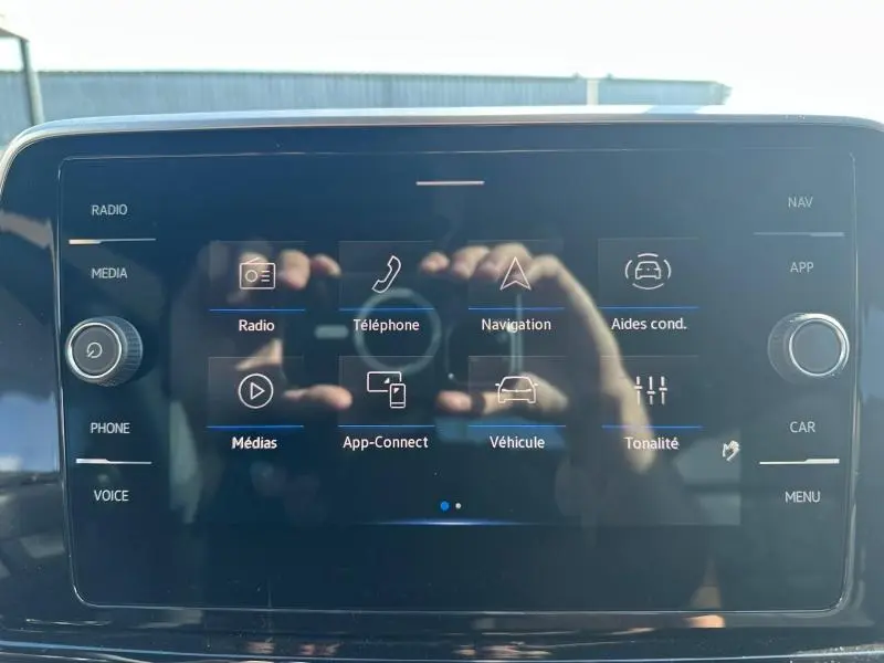 Écran tactile central du Volkswagen T-Roc 2025 affichant les menus radio, téléphone, navigation et aides à la conduite.