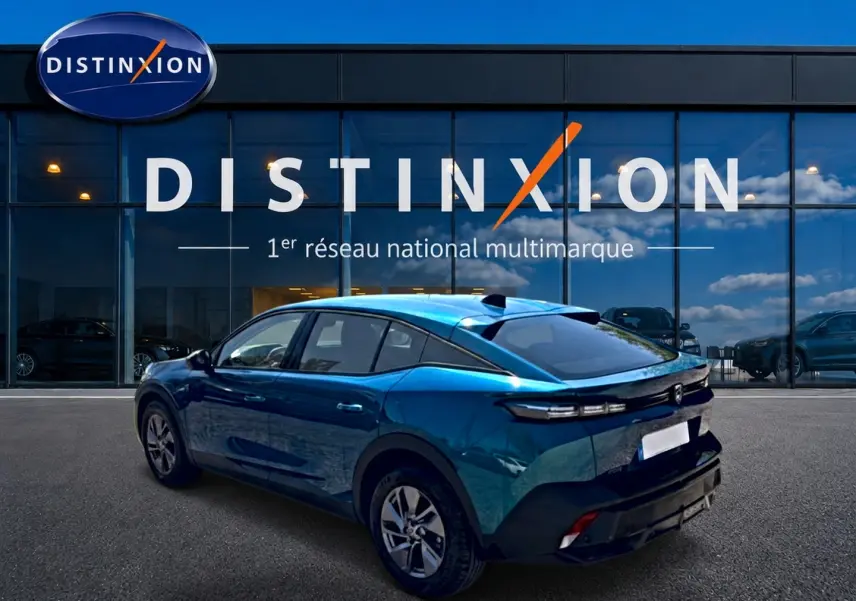 Vue 3/4 arrière droite d'une Peugeot 408 Hybrid 145 allure e-dcs6 bleu métallisé avec jantes alu devant une vitrine Distinxion.