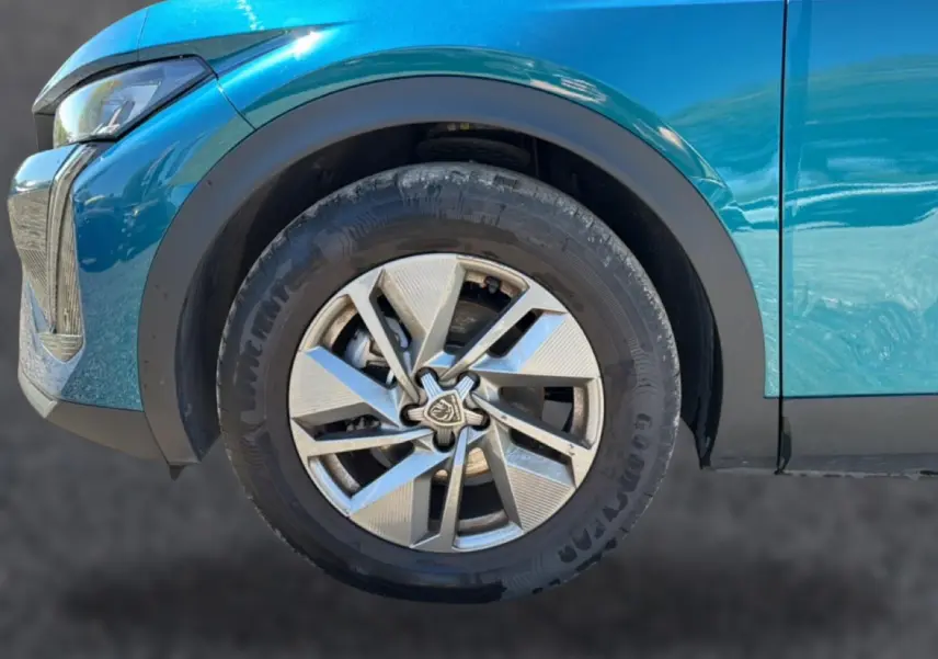 Gros plan sur la roue avant gauche d’une Peugeot 408 bleu 2025 avec jante alu au design moderne.