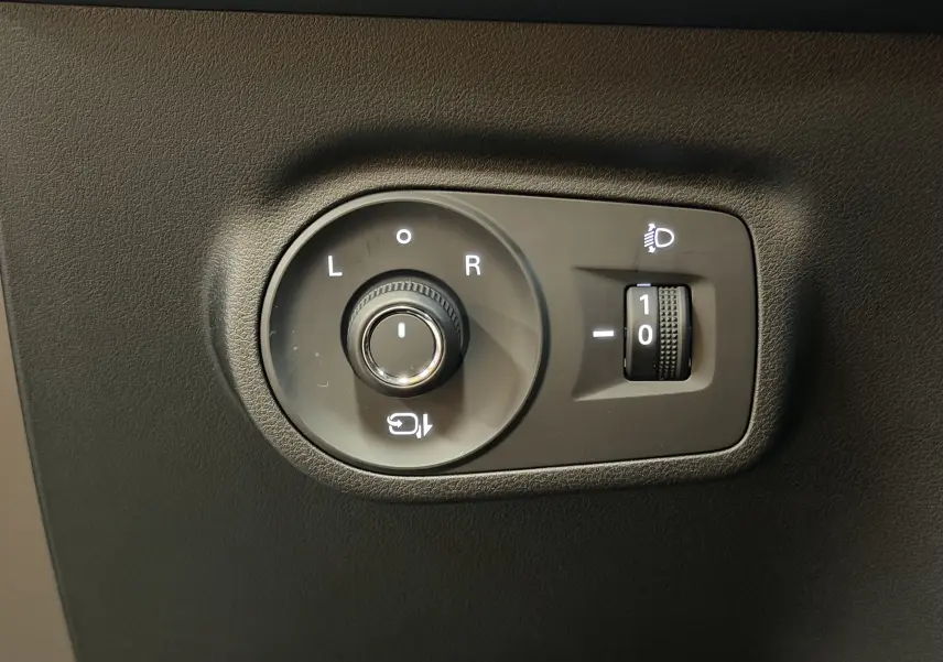 Gros plan sur les commandes de réglage des rétroviseurs et de l’éclairage du MG ZS noir, intérieur côté conducteur.