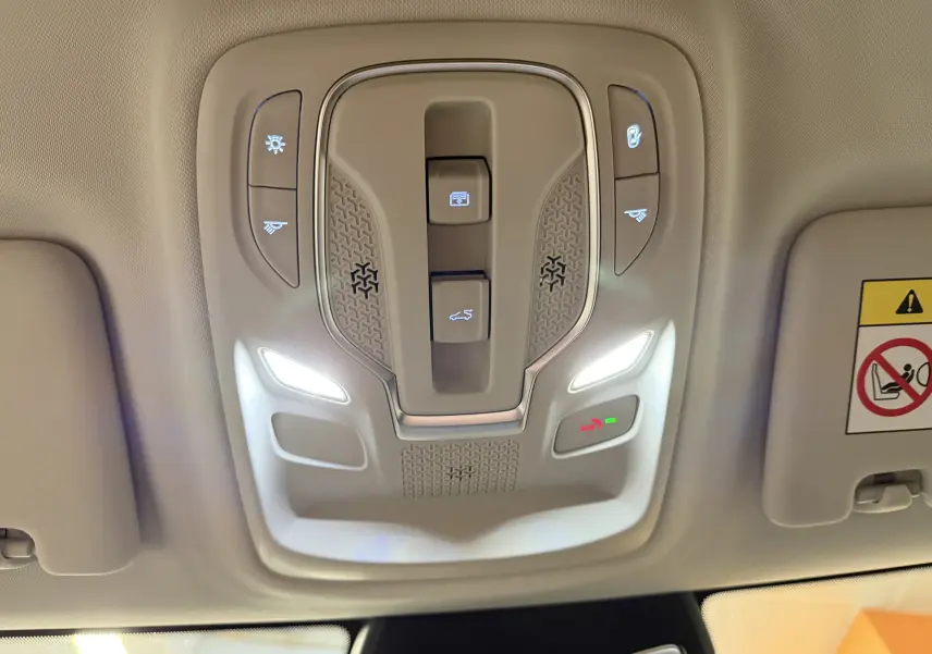 Vue en contre-plongée du panneau de commandes de toit intérieur beige du MG ZS 2026 avec éclairage LED et boutons fonctionnels.