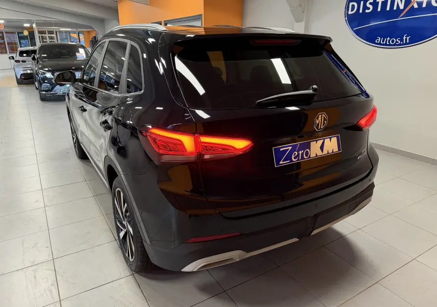 Vue 3/4 arrière droite du MG ZS noir 2026 avec feux arrière LED allumés et jantes alliage 18 pouces en showroom.
