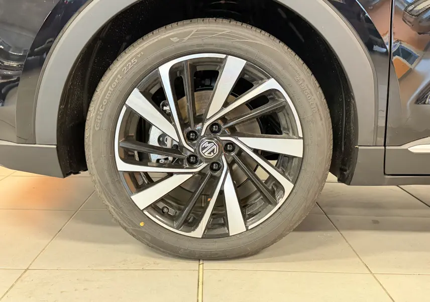 Gros plan sur la roue avant droite du MG ZS noir 2026 avec jante alliage bicolore et logo MG central.