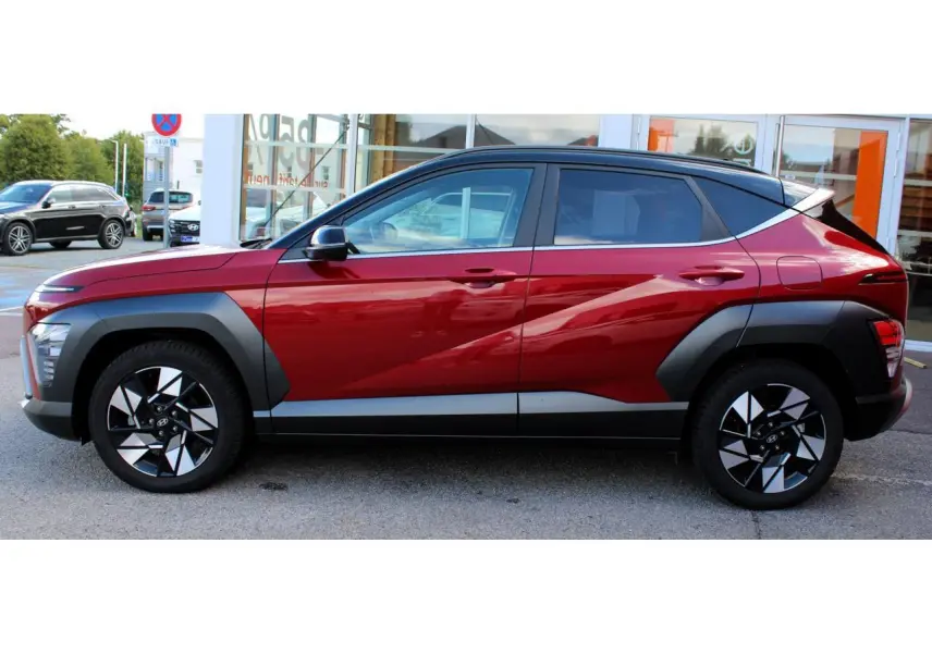 Vue latérale droite du Hyundai Kona 2024 rouge Ultimate Metal avec toit noir et protections d'ailes anthracite.
