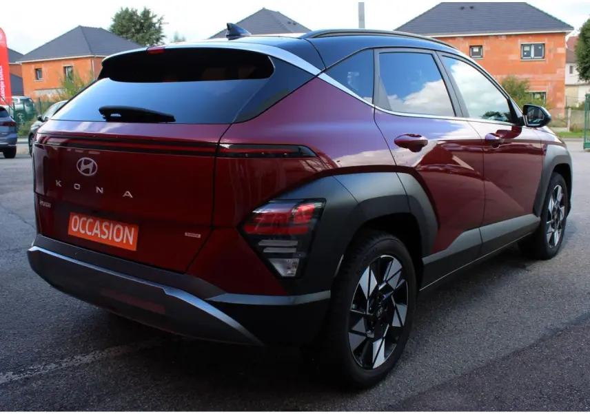 Vue 3/4 arrière droite d'un Hyundai Kona 2024 rouge Ultimate Metal avec toit noir et jantes alliage.