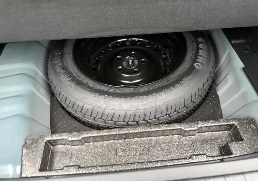 Vue du coffre ouvert montrant la roue de secours noire du Renault Arkana 2025, détail du rangement intérieur.