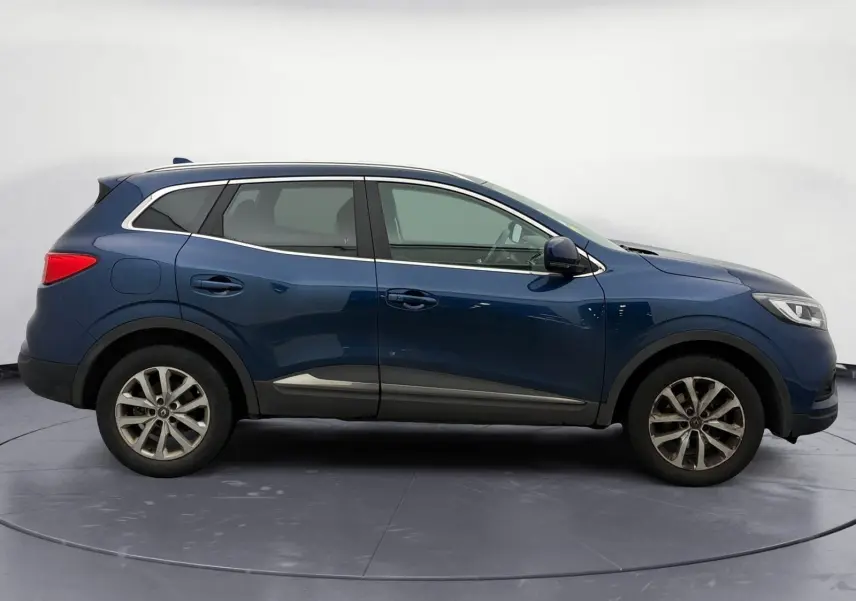 Profil droit d’un Renault Kadjar 1.5 Blue dCi 115 Business bleu cosmos, avec jantes alliage et barres de toit chromées.
