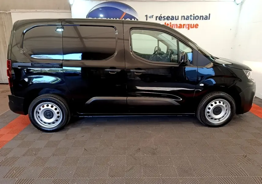 Profil côté droit d’un Peugeot Partner noir 2022 avec jantes acier et cloison pleine visible à l’arrière.
