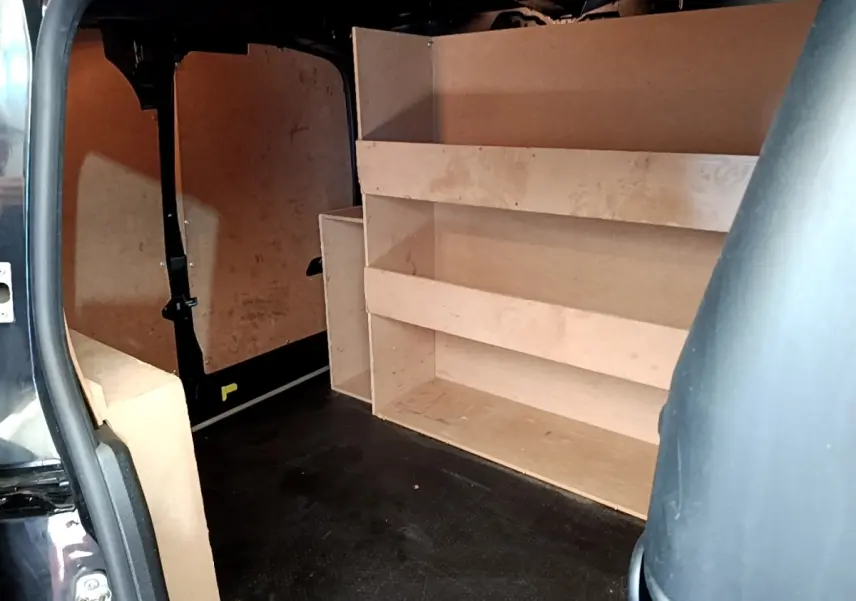 Vue intérieure arrière du Peugeot Partner noir 2022, montrant l'aménagement bois de rangement et la cloison pleine.