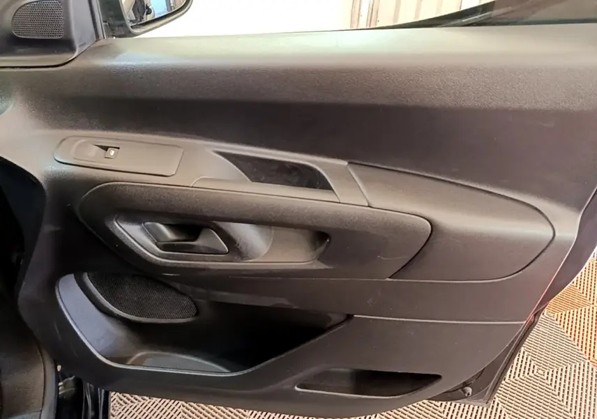 Vue rapprochée de la porte intérieure côté conducteur noire du Peugeot Partner 2022 avec commande de vitre et poignée intégrée.