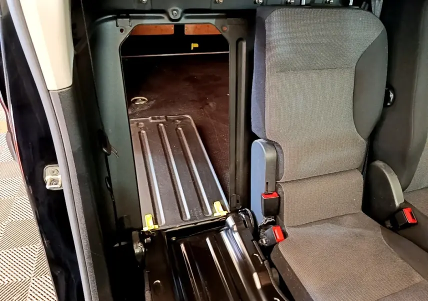 Vue intérieure montrant la cloison pleine et l'ouverture entre l'habitacle et la zone de chargement du Peugeot Partner noir.