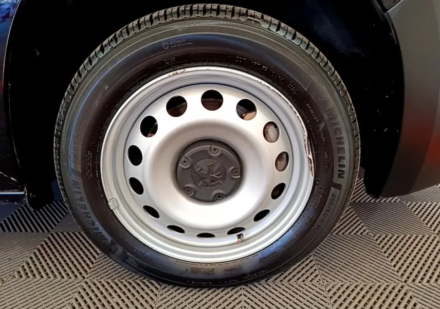Gros plan sur la roue avant droite en jante acier du Peugeot Partner noir, soulignant le pneu Michelin.