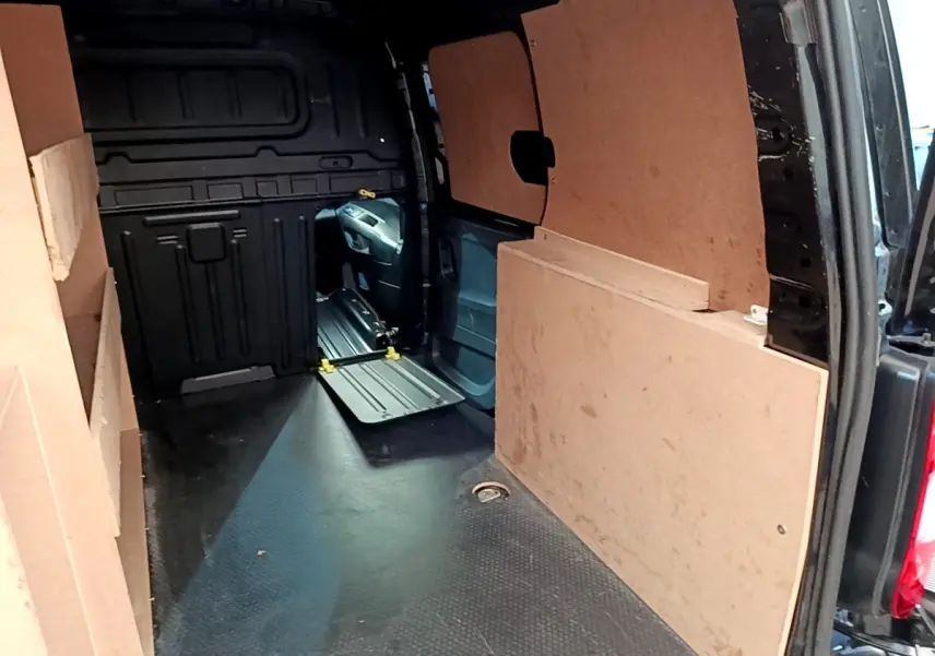 Vue intérieure arrière du Peugeot Partner noir 2022, montrant l'espace de chargement avec cloison pleine en bois.