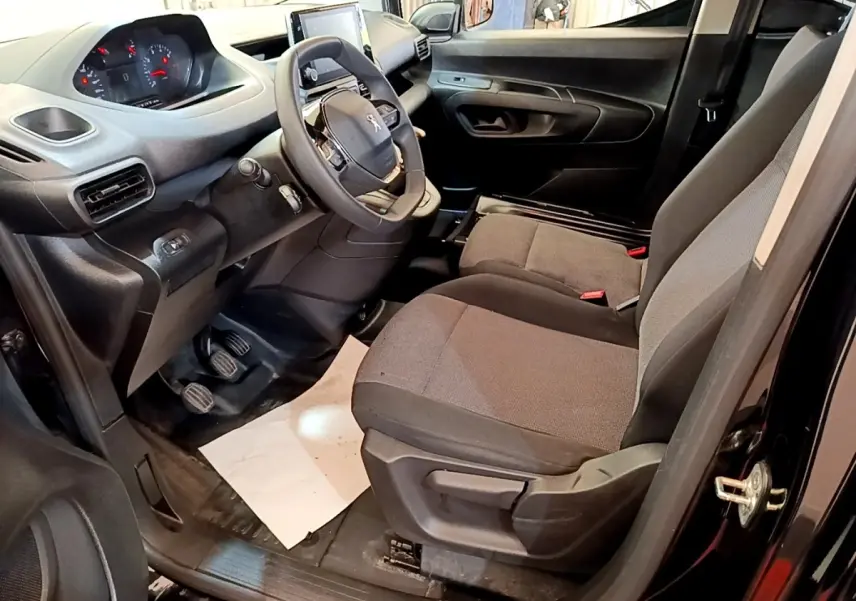 Vue intérieure côté conducteur du Peugeot Partner noir 2022, montrant le volant, tableau de bord et sièges avant.