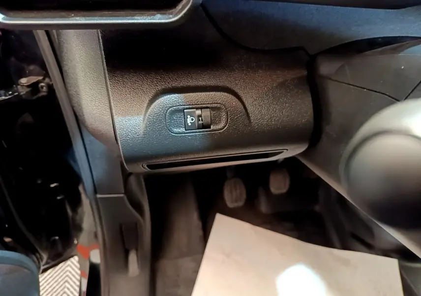 Détail intérieur côté conducteur du Peugeot Partner noir 2022, montrant le réglage manuel des phares et les pédales.