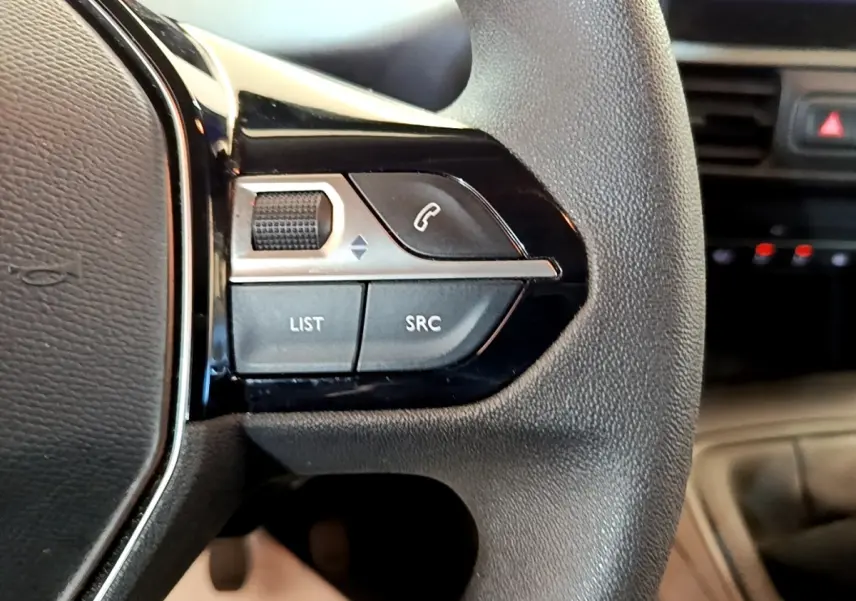 Gros plan sur les commandes gauche du volant noir du Peugeot Partner 2022, avec boutons d’appel et réglages audio.
