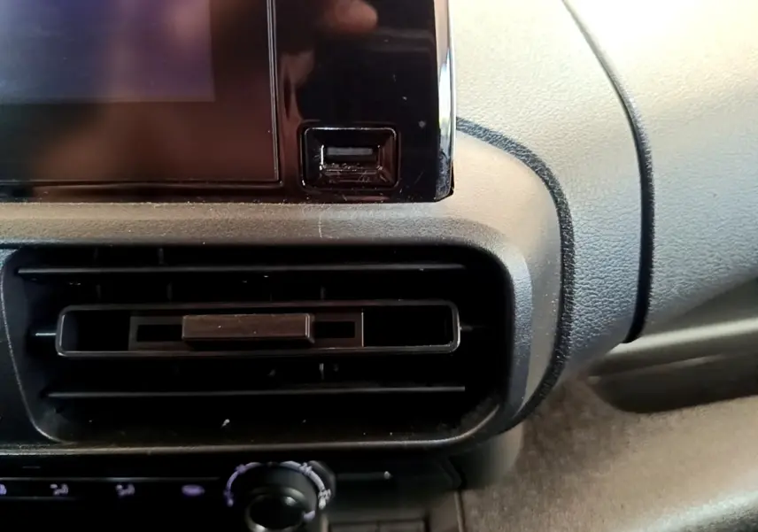 Gros plan sur la console centrale noire du Peugeot Partner 2022, montrant la sortie d’air et un port USB.