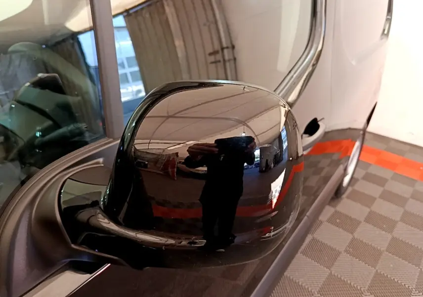 Rétroviseur extérieur noir côté conducteur d'un Peugeot Partner 2022 vu en gros plan avec reflet de l'environnement intérieur.