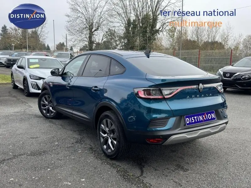 Vue 3/4 arrière droite d'un Renault Arkana 2025 bleu Zanzibar avec feux arrière reliés par un bandeau lumineux rouge.