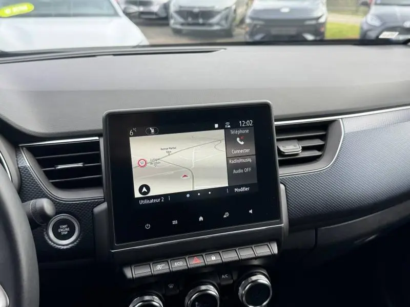 Vue intérieure centrée sur l'écran tactile du tableau de bord du Renault Arkana 2025, avec commandes et finition noire.
