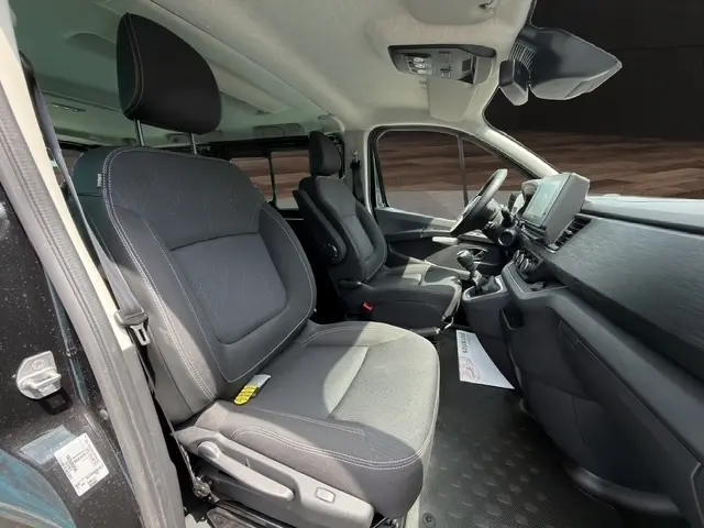 Vue intérieure côté conducteur du Nissan Primastar noir 2025, montrant les sièges avant et le tableau de bord avec écran tactile.
