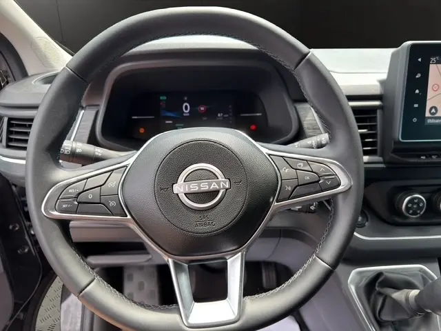 Vue rapprochée du volant en cuir noir du Nissan Primastar 2025 avec commandes multifonctions et tableau de bord digital.