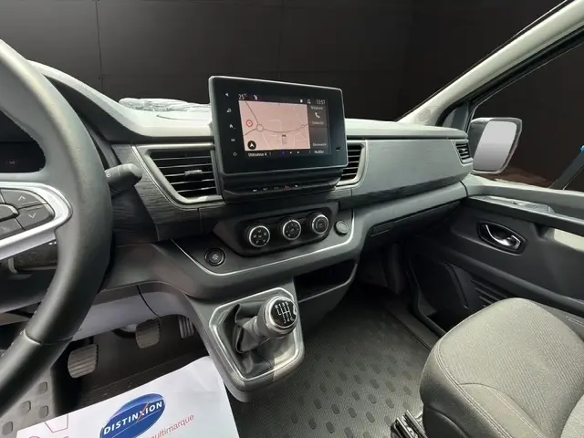 Vue intérieure côté conducteur du Nissan Primastar 2025 noir, avec écran tactile central et levier de vitesses manuel.