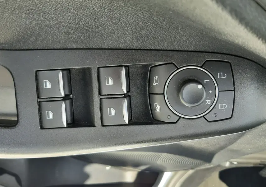 Gros plan sur les commandes de lève-vitres et réglage des rétroviseurs côté conducteur d’un Ford Puma blanc 2022.