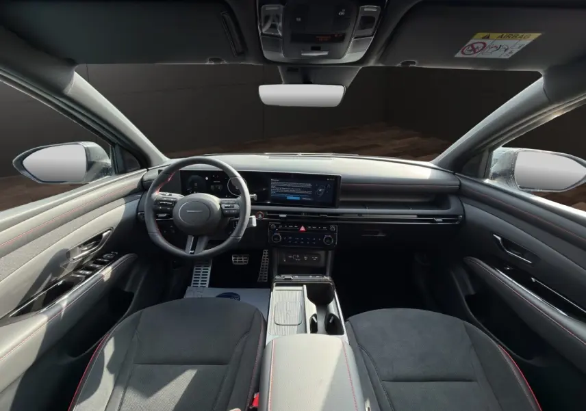 Vue intérieure avant du Hyundai Tucson gris clair 2026, tableau de bord moderne avec écran tactile large et volant multifonctions.