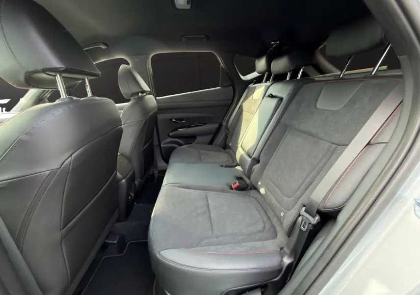 Vue intérieure côté droit des sièges arrière gris foncé avec surpiqûres rouges du Hyundai Tucson 1.6 Hybrid 2026.