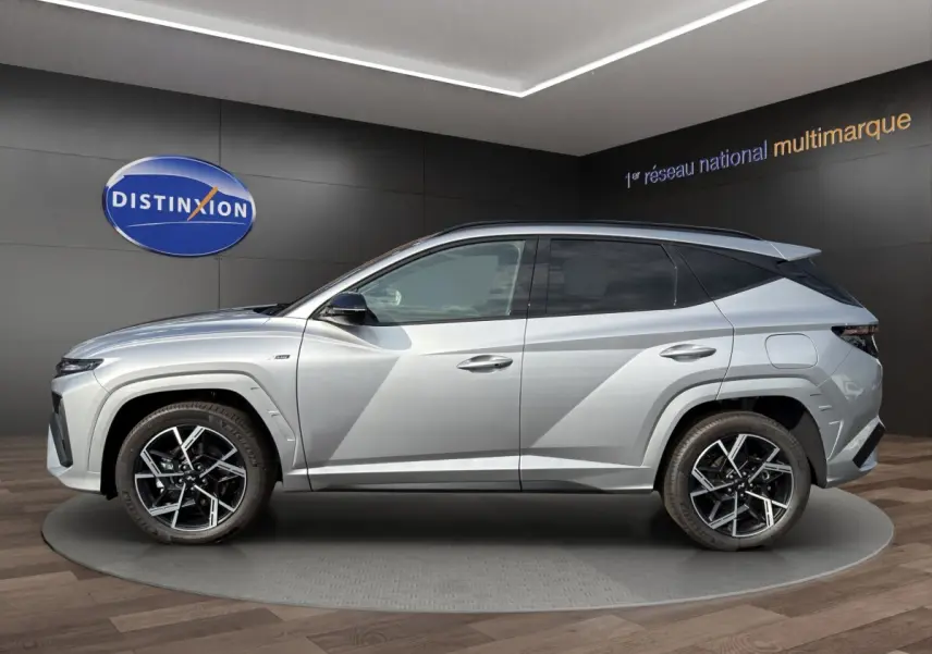 Profil droit du Hyundai Tucson 1.6 Hybrid N Line gris clair avec jantes alliage et lignes anguleuses marquées.