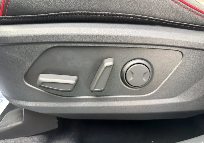 Détail des commandes de réglage électrique du siège avant avec surpiqûres rouges sur cuir noir du Hyundai Tucson 1.6 Hybrid 2026.