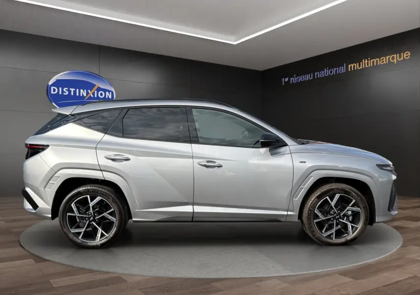 Vue latérale droite du Hyundai Tucson gris clair 2026 avec jantes alliage noires et toit noir contrasté.