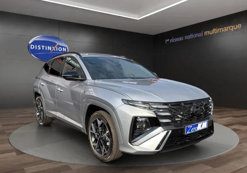 Vue 3/4 avant droit du Hyundai Tucson gris clair 2026 N Line avec calandre noire et jantes alliage distinctives.