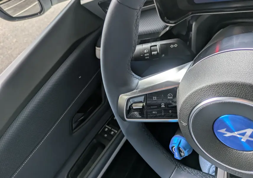 Vue rapprochée du volant noir avec logo bleu Alpine et commandes multifonctions côté gauche dans l'Alpine A290 220CH GTS.