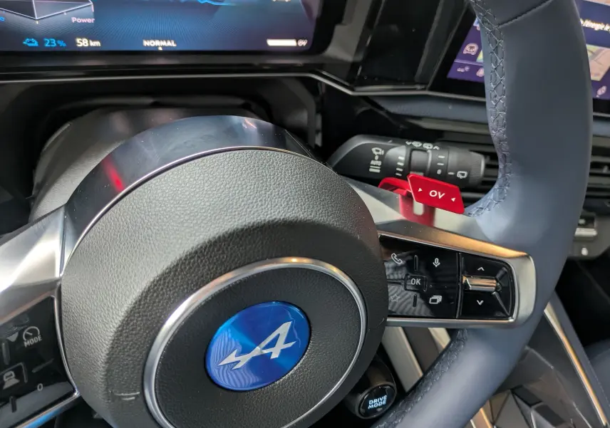 Gros plan sur le volant bleu Alpine de l'Alpine A290 220CH GTS électrique, avec commandes intégrées et palettes rouges.