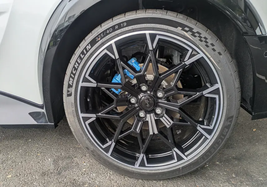 Gros plan sur la jante alliage 19'' Snowflake noir brillant et étrier de frein bleu Alpine d'une Alpine A290 blanche toit noir.