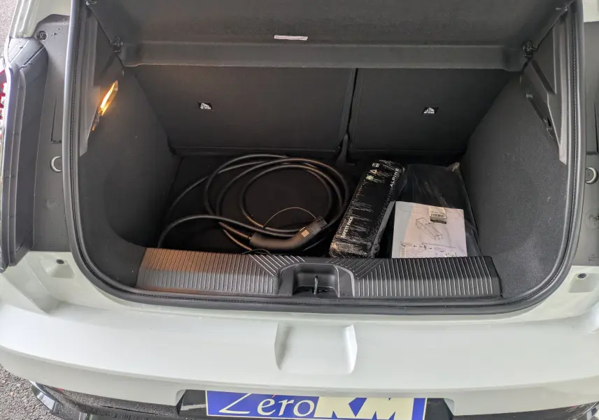 Coffre ouvert vu de dessus d'une Alpine A290 220CH GTS blanc toit noir avec câble de recharge et accessoires visibles.