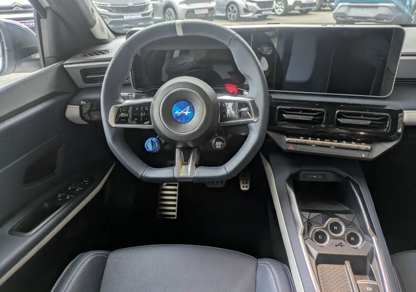 Vue intérieure centrée sur le volant bleu Alpine et la console centrale du tableau de bord de l'Alpine A290 220CH GTS.